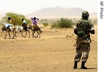 Sudanese travel on their donkeys as a Rwandan soldier assigned to the African Union Mission in Sudan stands guard on the outskirts of Thabit, North Darfur 