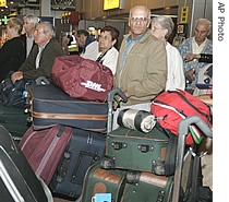 Passengers wait to check in with a pile of luggage at Heathrow Airport terminal 4, London, Tuesday, August 15, 2006