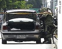 Bomb squad members inspect a car loaded explosives near the house of Prime Minister Thaksin Shinawatra in Bangkok, 24 August 2006 