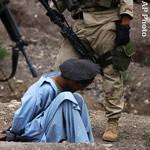 US soldiers stand guard by an Afghan prisoner near Zunchorah Village in Khost  