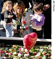 Mourners toss flowers into a reflecting pool during a ceremony Monday, September 11, 2006 at the World Trade Center in New York