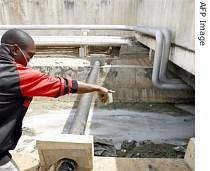 A man points to an open drain where toxic waste was dumped, in an industrial zone of Abidjan
