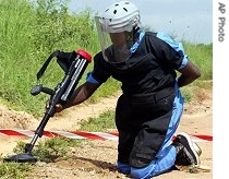 A UN contractor uses a metal detector to search for mines planted along a dirt road in Juba, Sudan