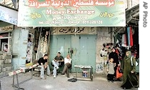 Palestinians sit in front of damaged currency exchange office raided by Israeli army in Ramallah, Wednesday, Sept. 20, 2006