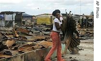 Patricia Oga collects sheets of metal roofing from remains of her house after Nigerian military burned down village in retaliation for kidnapping of an oil worker, October 6, 2006