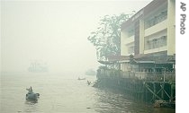 An Indonesian man rows his boat on Kapuas river amid haze from burning brush fires, in Pontianak, Borneo island, Indonesia, Oct. 5, 2006.