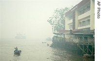 An Indonesian man rows his boat on Kapuas river amid haze from burning brush fires, in Pontianak, Borneo island, Indonesia, Oct. 5, 2006.