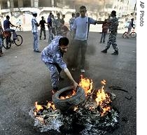 Palestinian police officer burns tires during a demonstration demanding payment of salaries in Gaza City, October 22, 2006 