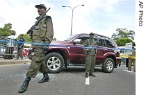 Sri Lankan Army soldiers stand guard next to bullet-ridden vehicle of slain Tamil politician Nadaraja Raviraj at crime scene in Colombo