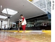 A worker sweeps rain water from the main gate of newly-built Cebu International Convention Center