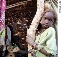 A girl stands near a straw hut in a refugee camp, near Goz Beida, Chad 19 April 2006