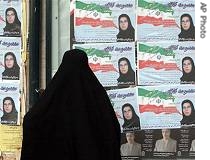 Iranian woman, wearing the traditional Islamic black veil, looks at campaign posters of female candidate Masoumeh Kolahi, in Tehran, 13 Dec 2006