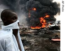 A boy covers his face as he walks past burning vehicles and corpses following an early morning pipeline explosion in Lagos, Nigeria, 26 Dec 2006