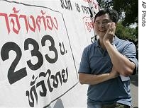 Thai worker stands next to a sign calling for increased minimum wage in Thailand (File photo)