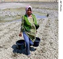 A farmer carries buckets of water collected from a drying pond in Rembang, Central Java, Indonesia 