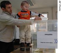 An ethnic Albanian man casts his ballot with his son at a polling station in Presevo, 21 Jan 2007