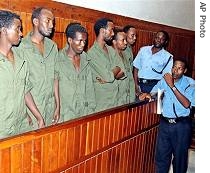 Some of the ten Somali men accused of piracy stand in the dock under guard of Kenyan police officers in this 3 Feb 2006 file picture in the court in Mombasa