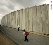 Palestinians walk next to Israel's controversial separation barrier