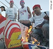 Protesters burn a mock ASEAN logo and a US flag during their 