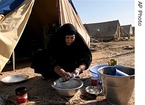 An Iraqi Shiite woman washes her dishes in a camp for Baghdad's displaced Shiite families in Diwaniyah