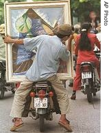 A worker hangs onto an abstract painting while transporting it on the back of a motor bike through the streets of Hanoi (File)
