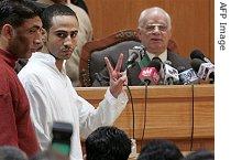 Mohamed Essam Ghoneim El Attar flashes the victory sign while being escorted to speak with State Court Judge Sayed al-Gohari (R)during his second day in court in Cairo 28 February 2007