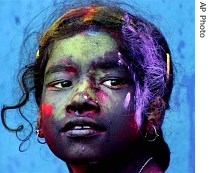 A girl, color smeared on her face, looks on during 