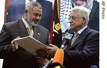 Palestinian President Mahmoud Abbas, (r) hands Ismail Haniyeh a letter of appointment authorizing him to form new coalition government in Gaza City, 15 Feb 2007 
