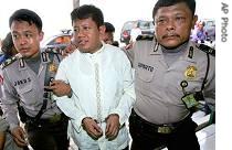 Alleged mastermind of the 2005 terror attack on Sulawesi island Hasanuddin, center, is escorted by police officers prior to his trial at a district court in Jakarta, 21 Mar 2007