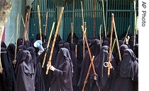 Veiled female students Islamic seminary hold bamboo sticks as they chant slogans during protest, 28 Mar. 2007 