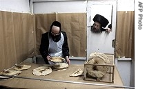 Ultra Orthodox Jewish man watches from door as another checks baked Matzoth or unleavened bread in Jerusalem, 2 Apr 2007