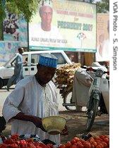 A billboard bearing Umaru Yar'Adua's face looks down on a street vendor in Katsina, Nigeria, 19 Mar 2007