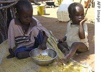 Somali refugee children eating a portion of maize provided by humanitarian agencies at the Kenyan-Somali border point of Liboi, 6 Jan 2007