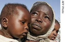 A displaced Sudanese woman carries her sons in the Otach Displaced Persons camp in the city of Nyala in Sudan's strife-torn Darfur region, 22 Feb 2007