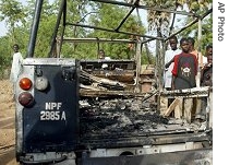 People stand and look at a police vehicle, torched by gunmen in Kano, Nigeria, 17 Apr 2007