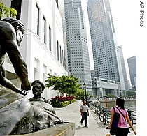People walk pass a statue of traders from the olden days in Singapore, while the financial distric is seen in the background (File)