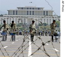 Pakistans paramilitary troops stand alert with riot gears behind a barbed wire at a road leading towards the Supreme Court in Islamabad, 02 May 2007