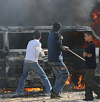 Palestinian youth gather around a burning vehicle following factional clashes in Gaza City, 14 May 2007