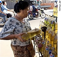 Cambodian Tang Solin, 59, pours gasoline into a smaller bottle at her road-side store in the capital Phnom Penh, Cambodia (File)