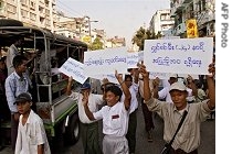 Protesters shout slogans for better living conditions while holding placards near a market in central Rangoon, 22 Feb 2007