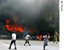 Supporters of Pakistani opposition party run after setting on fire a vehicle during a gun battle between two rival groups in Karachi, 12 May 2007