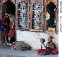 An old monk chants prayers on a street corner in Paro 