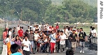 Bhutanese refugees carry injured and shout slogans, as Indian policemen are seen in background, in border town of Karkarvitta, 29 May 2007