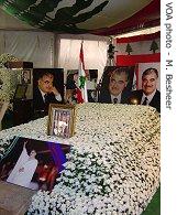 Hariri's tomb is covered in white flowers with a Lebanese flag overhead