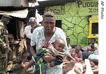 A woman with facial injuries runs away with her baby next to people rounded up during fighting between police and Mungiki sect in Nairobi's Mathare slum, 07 Jun 2007