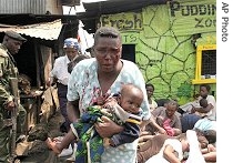 A woman with facial injuries runs away with her baby next to people rounded up during fighting between police and Mungiki sect in Nairobi's Mathare slum, 07 Jun 2007 