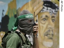Palestinian Hamas militant talks on radio in front of a mural showing the late Fatah leader Yasser Arafat outside his former compound in Gaza City (16 Jun 07)