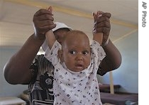 A six-month-old, HIV-positive baby is held up by a woman who did not want to be identified in a home for the destitute in Bulawayo, Zimbabwe (2005 photo)   