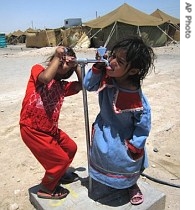 Iraqi children drink water from taps at a refugee camp for internally displaced people outside Najaf, Iraq, 16 June 2007