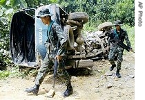 Thai soldiers examine the wreckage of a pickup truck which was hit by a bomb while their colleagues were riding on for a morning patrol in Yala province, southern Thailand, 15 Jun 2007